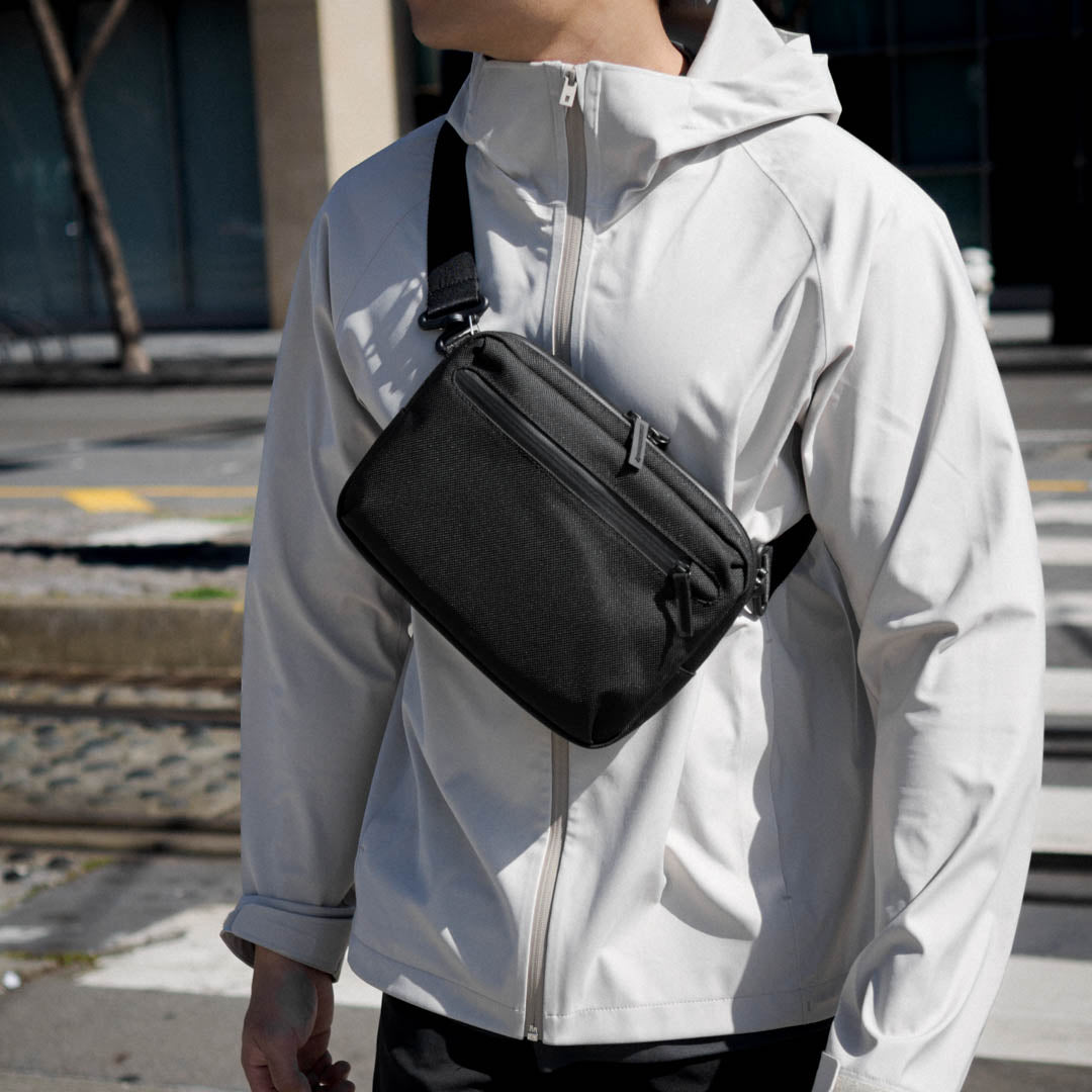 Model carrying the Essentials Case by Rework Gear in sling mode while crossing the street.