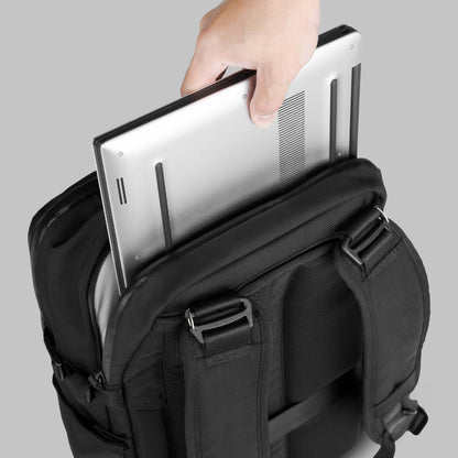 Person inserting a laptop case into the laptop compartment of the 22L Reset Pack by Rework Gear.