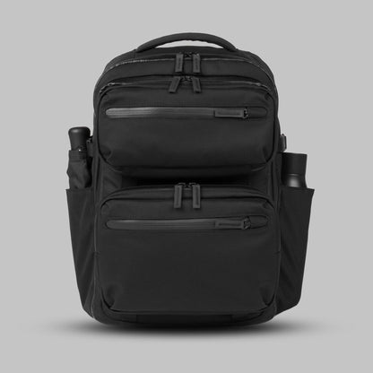 Modular backpack called Reset System sitting against a gray background with a water bottle and umbrella in its side pockets.