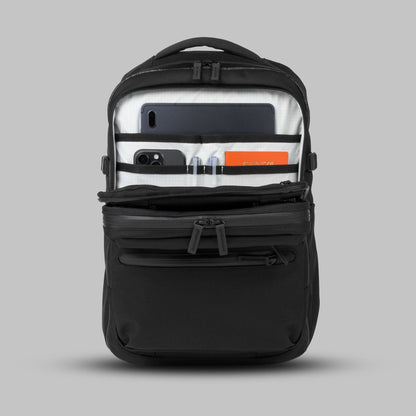 Open front admin compartment of a modular backpack called Reset System packed with essential items against a gray background.